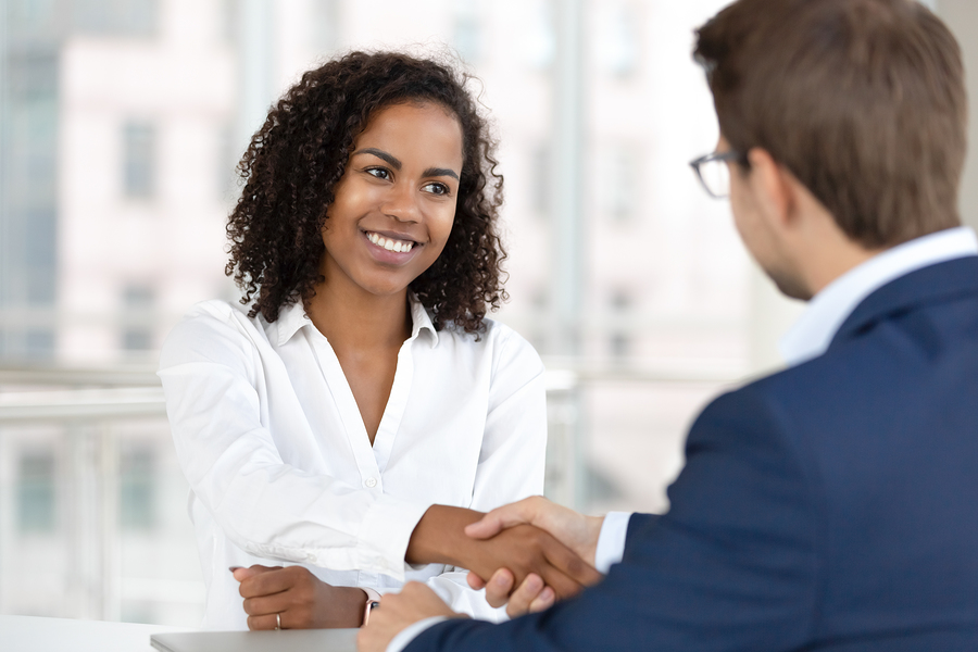 Smiling HR manager giving a handshake to a IT contract staffing candidate at job interview.