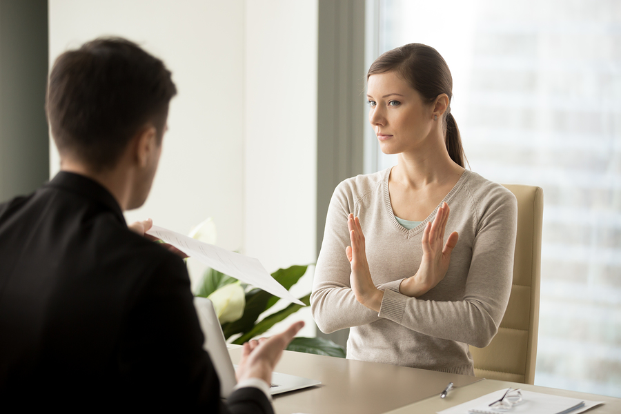 Skeptical young woman rejecting counter offer from current employer when sitting at desk in front of a manager.