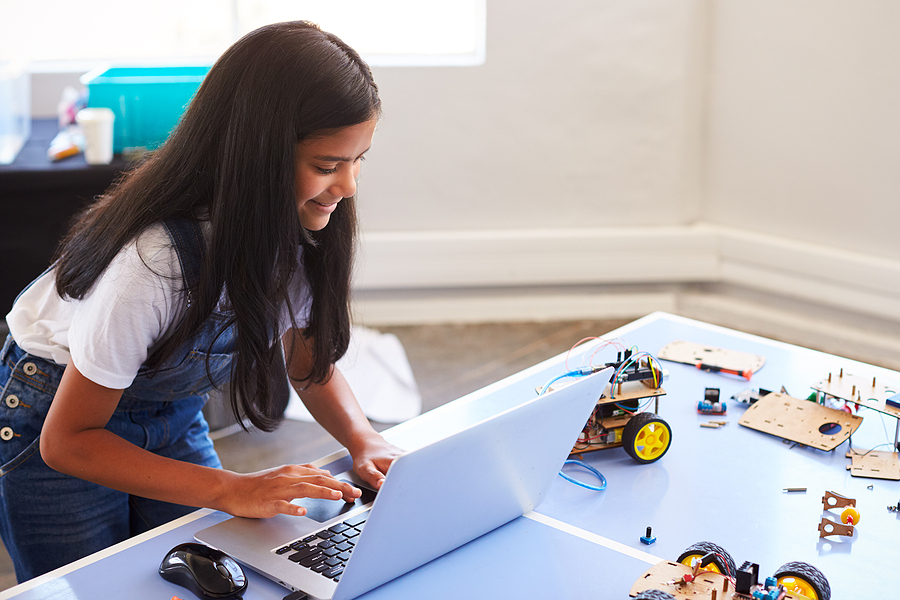 Female middle school student building And programing robot vehicle in after school computer coding class, just one way to foster interest in a technology career.