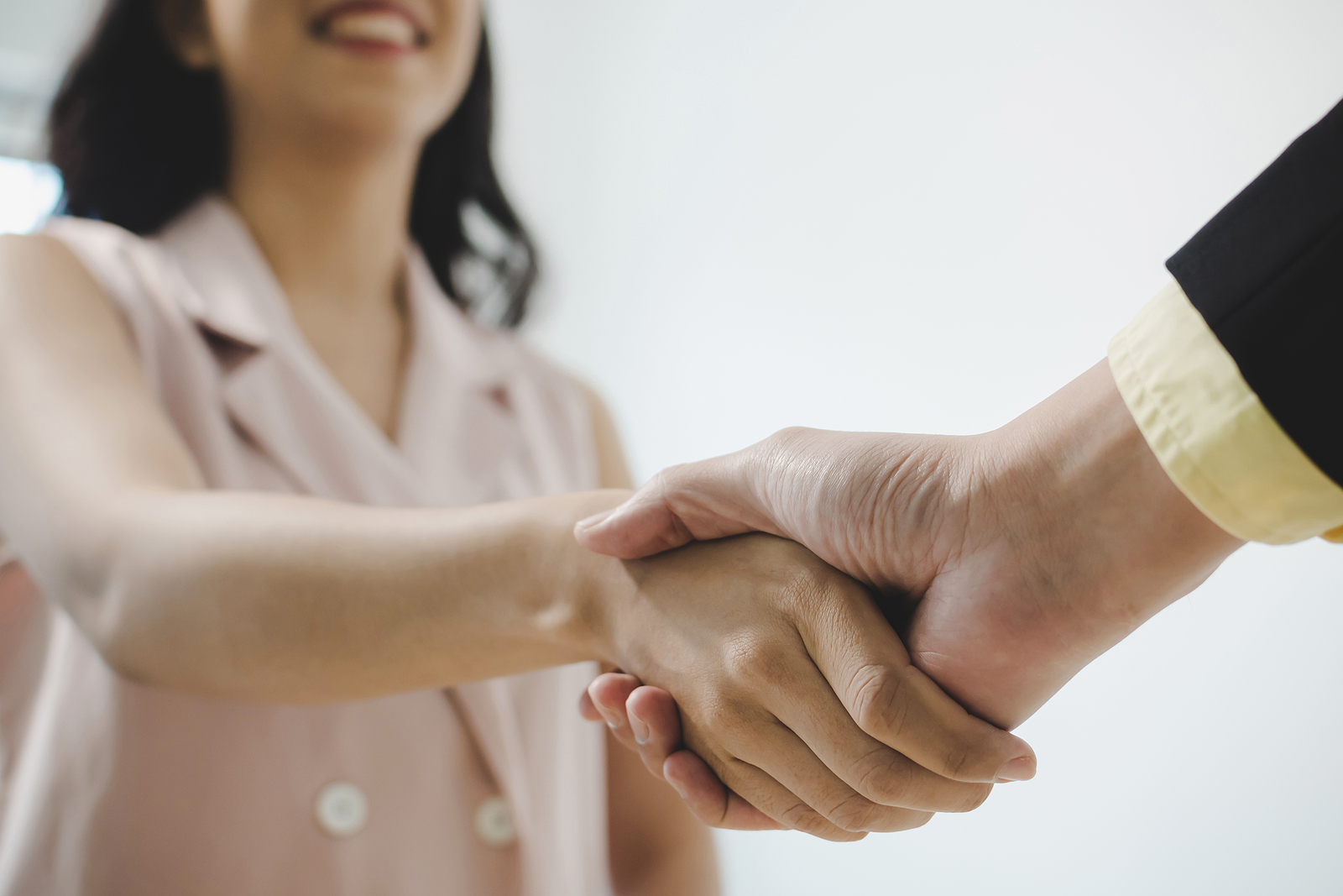 Young Woman Shaking Hands with Employer over Successful Contract Negotiations